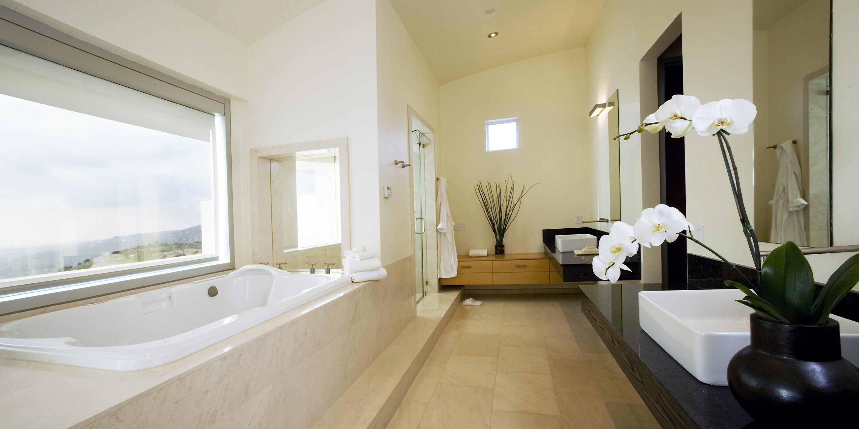 Elegant bathroom with a large bathtub, scenic window, and white orchid decoration on the countertop.